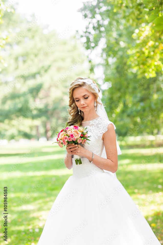 Beautiful bride outdoors in a park with wedding bouquet. Beautiful bride outdoors in a park with wedding bouquet.
