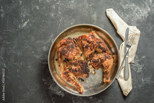 Grilled chicken Tabaka on dark black table. Georgian cuisine