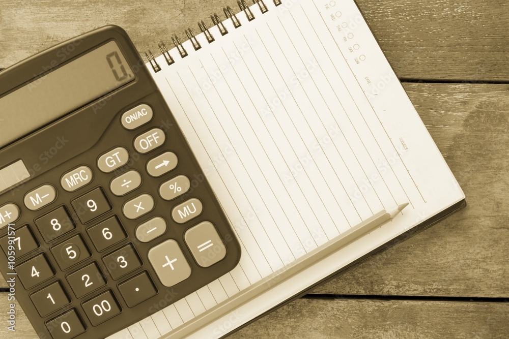 Blank notbook, calculator and pen laying on it on office wooden Blank notbook, calculator and pen laying on it on office wooden
