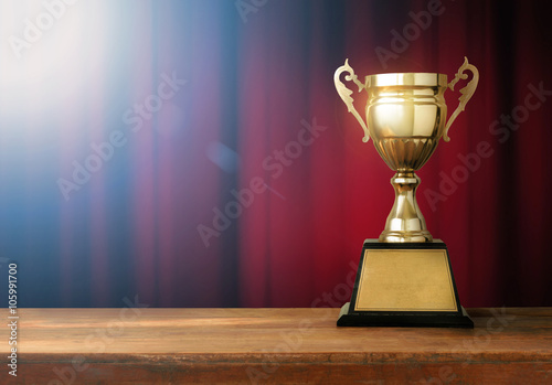 champion golden trophy on wood table with spot light and Red clo