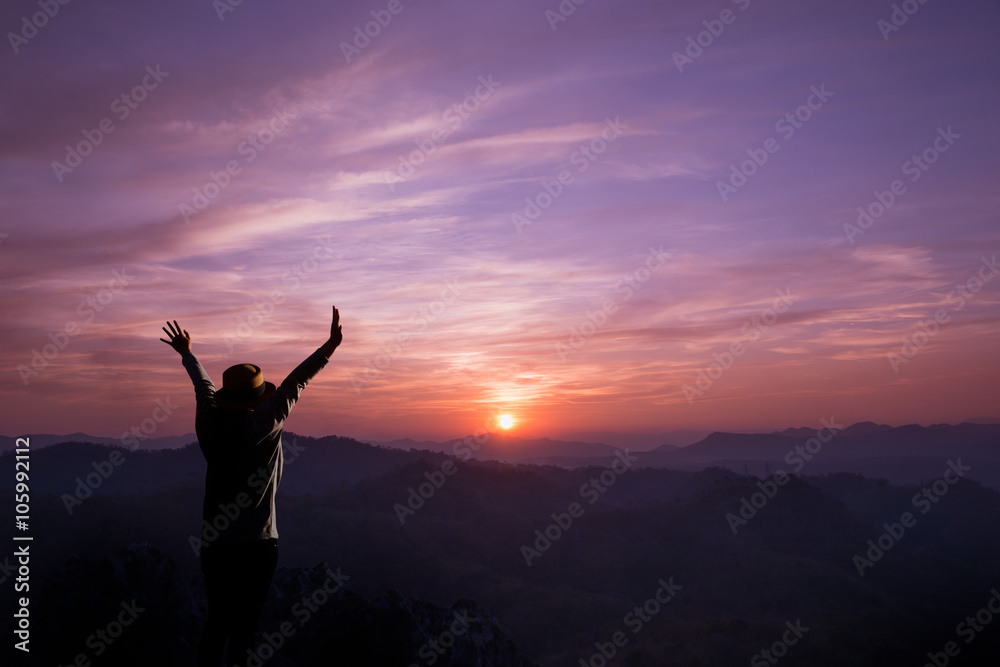 Young woman cheering open arms at mountain and sunset