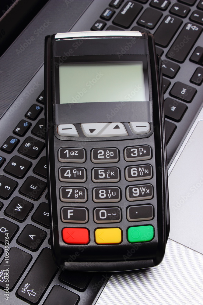 Payment terminal on laptop keyboard, finance and banking concept
