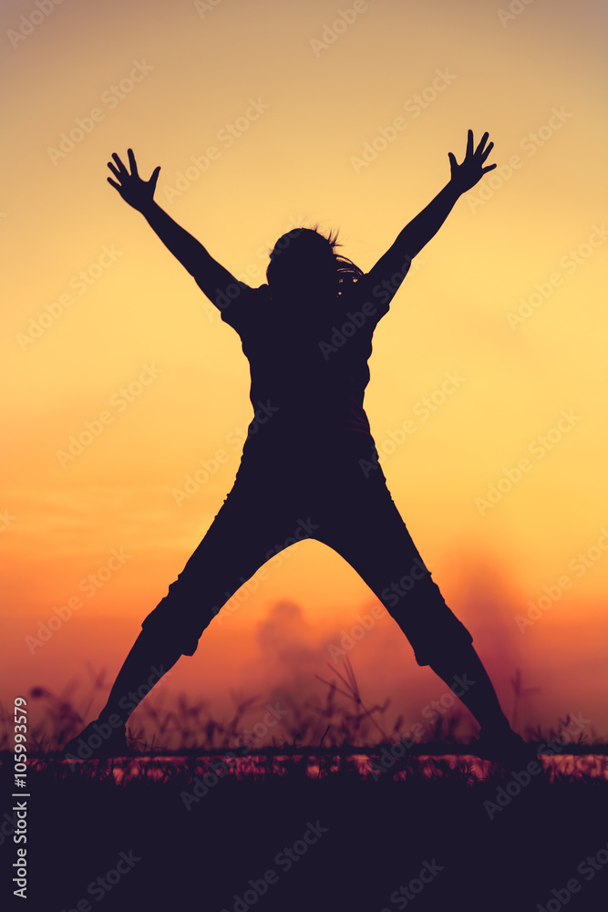 Silhouette of woman jumping against sunset. Young girl enjoying