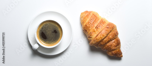 Overhead view of cup of black coffee and freshly croissant