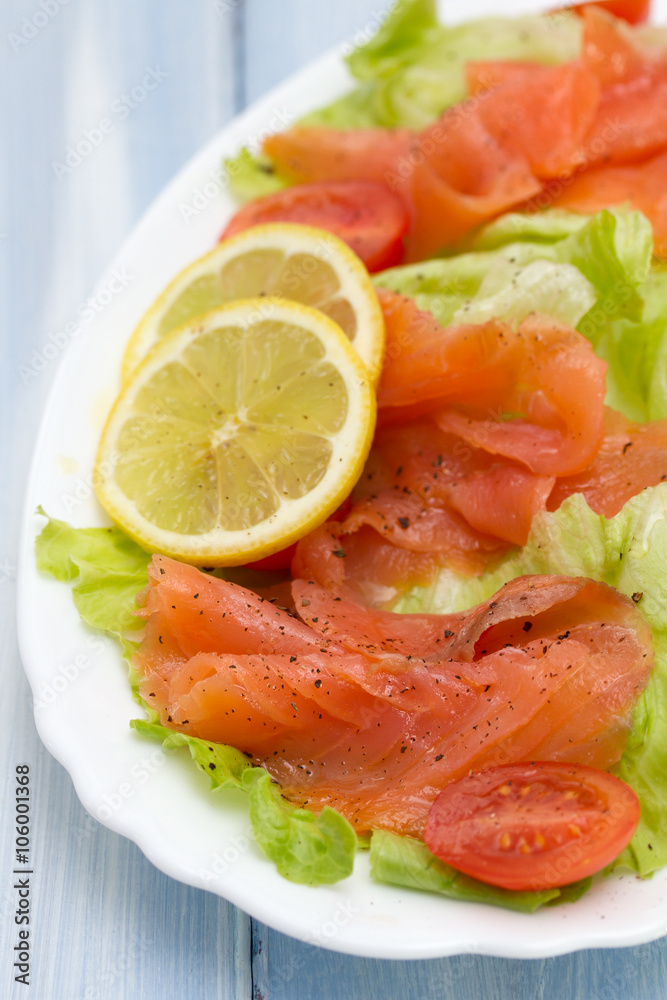 salad with smoked salmon on white dish on blue wooden background