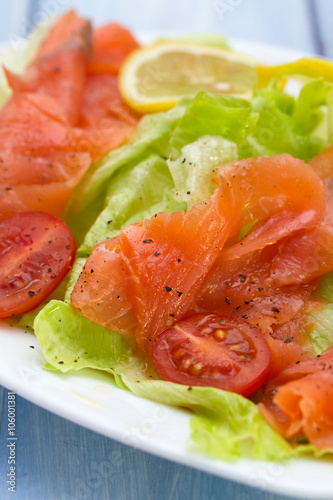salad with salmon on white dish on blue background