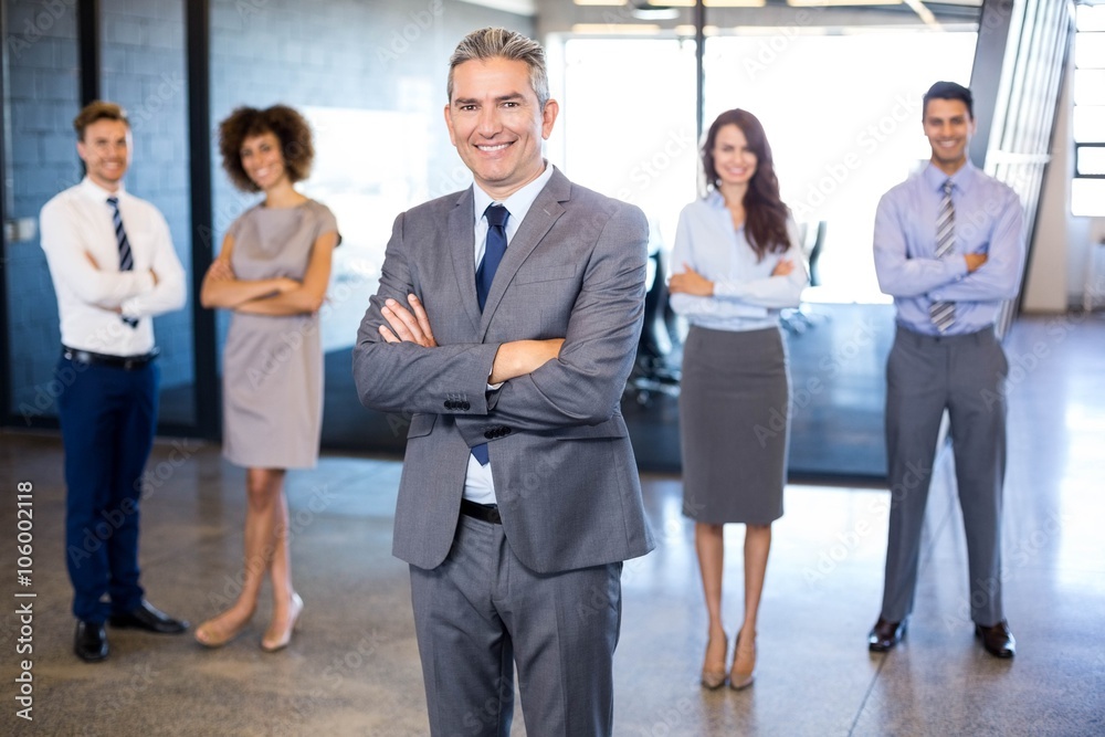 Businessman smiling at camera while his colleagues standing Businessman smiling at camera while his colleagues standing