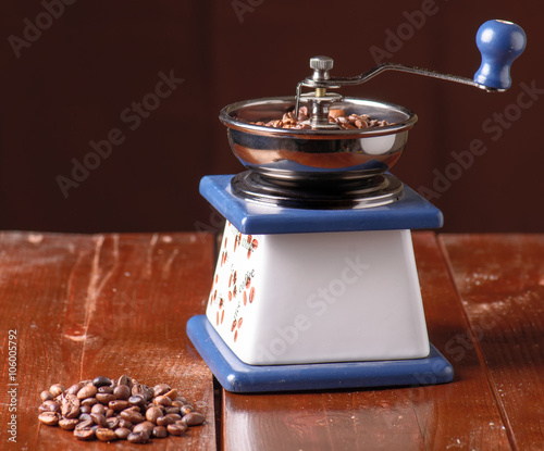 Old vintage coffee mill and spilled roasted hot beans.