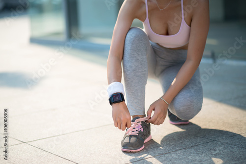Fototapeta Naklejka Na Ścianę i Meble -  Female jogger tying shoes before running outdoors