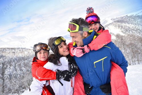 Parents giving piggyback ride to kids on ski slope