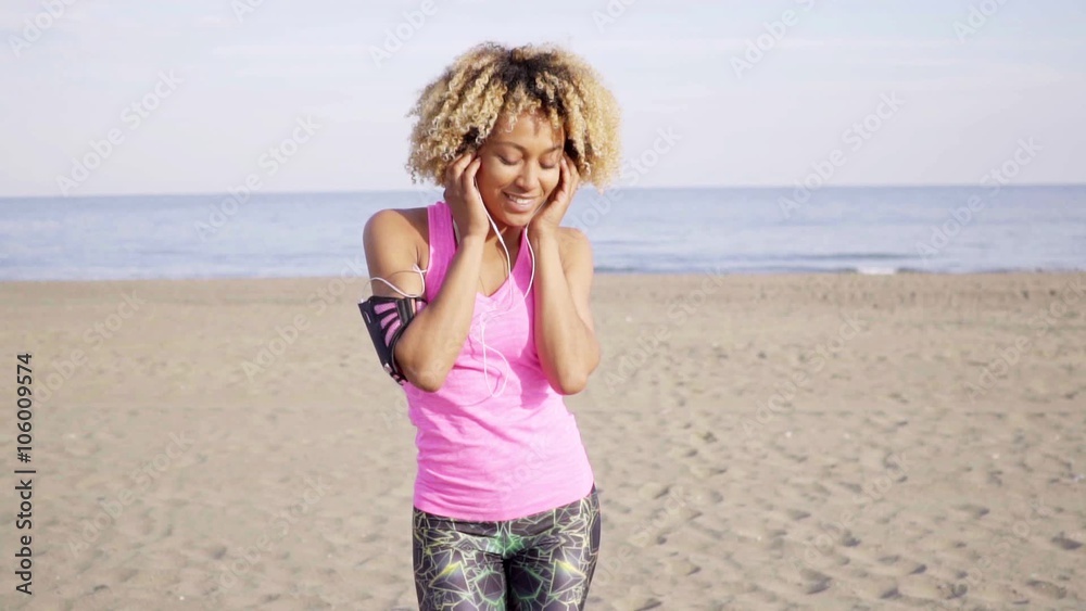 Sexy shapely young woman with an afro hairdo on a beach walking towards the camera with a friendly smile Sexy shapely young woman with an afro hairdo on a beach walking towards the camera with a friendly smile