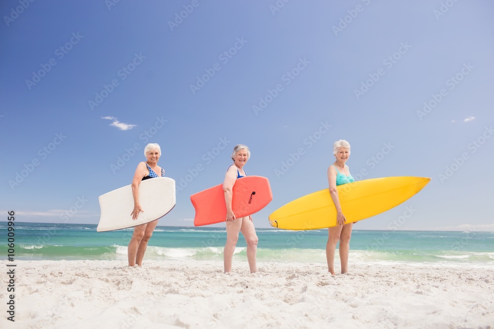 Senior woman friends holding surfboard