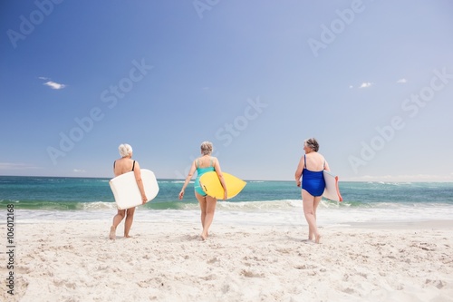 Senior woman friends holding surfboard
