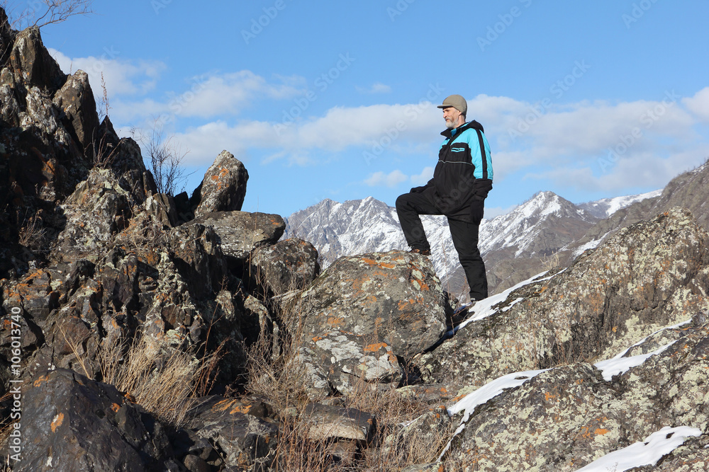 The man with a beard in a black jacket going by the rock in the mountain district, Altai, Russia
