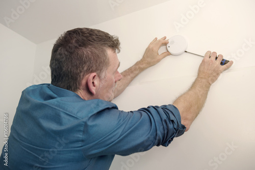 handsome man repairing a smoke detector photo