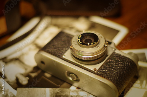 Vintage photo camera with old pictures on wooden table