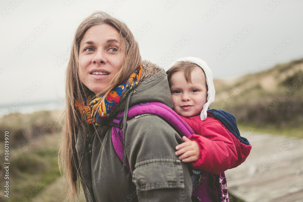 Mother carrying her child in a backpack outdoors Mother carrying her child in a backpack outdoors