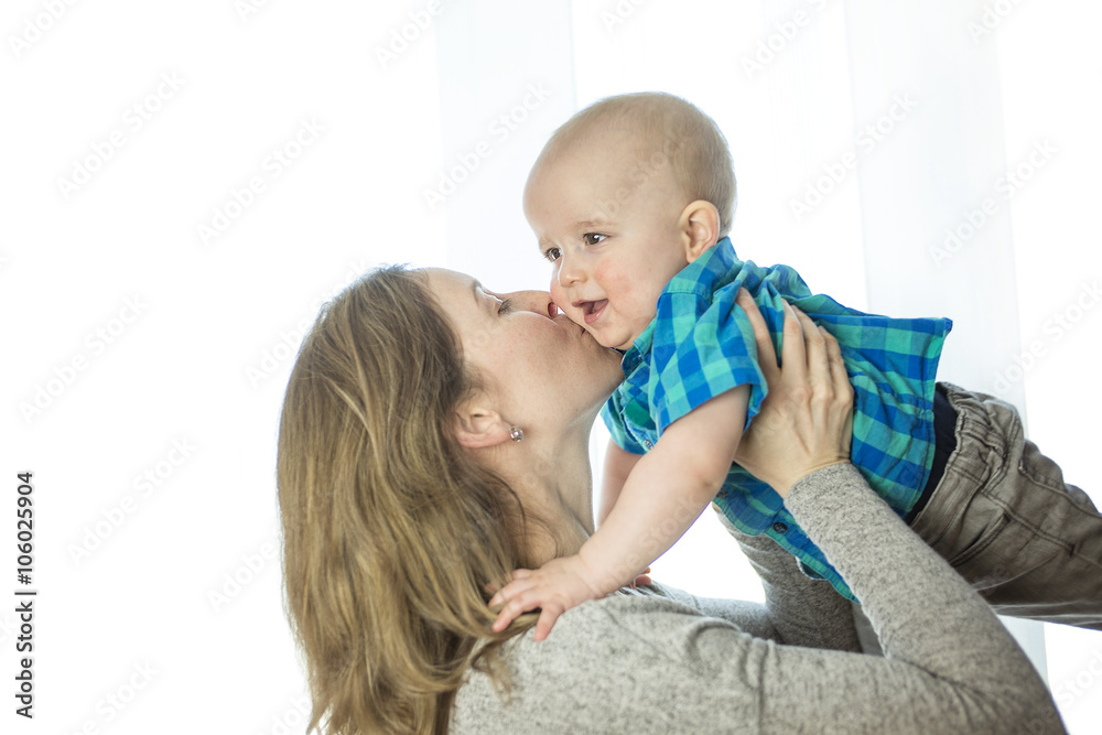 Loving mother playing with her baby close to a window Loving mother playing with her baby close to a window