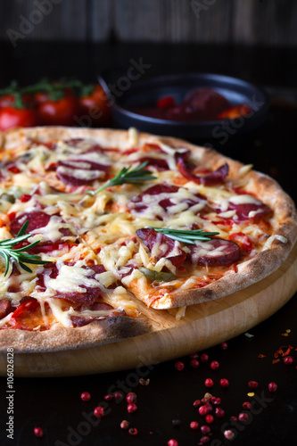 Delicious pizza with salami, tomatoes and hot peppers