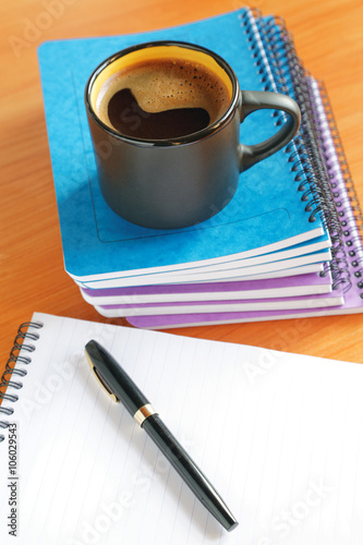 cup of coffee on the office desk with notebook and pen