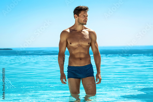 Young handsome man posing in swimming pool photo