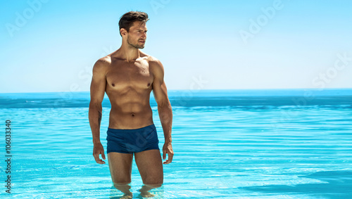 Panoramic photo of sexy man posing in swimming pool photo