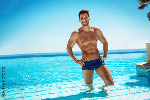 Summer photo of muscular smiling man in swimming pool photo