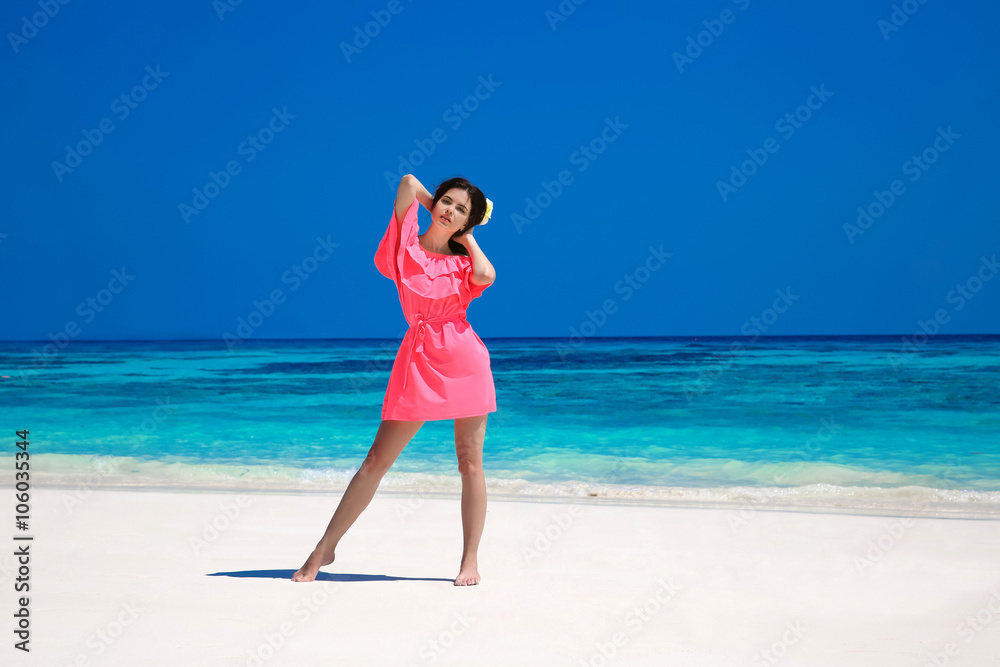 Woman on the beach. Beautiful slim girl model in red dress resti