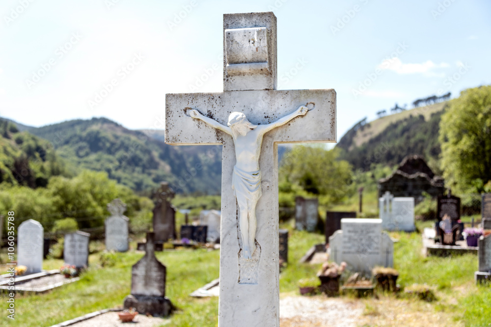 Irish graveyard with Jesus on a white cross and hills in the background
