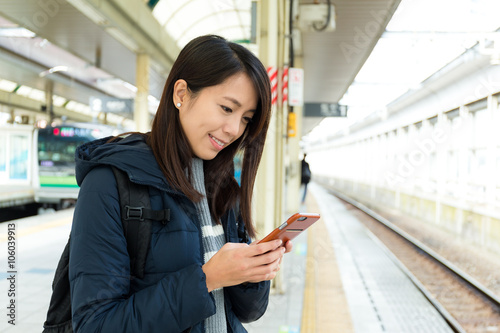 Woman usinf mobile phone at train platform