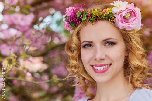 Woman with flower wreath against pink tree in blossoom photo