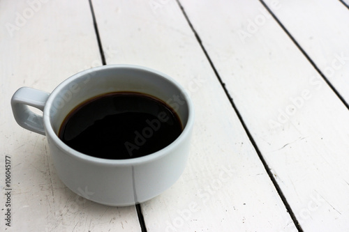 Cup of black coffee on white wooden table
