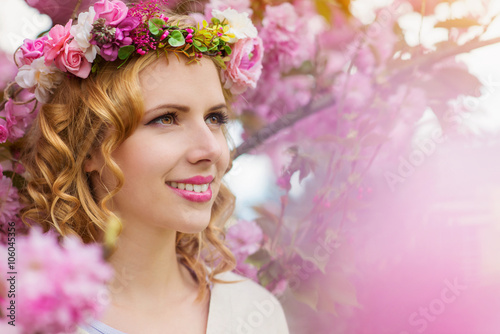 Woman with flower wreath against pink tree in blossoom photo