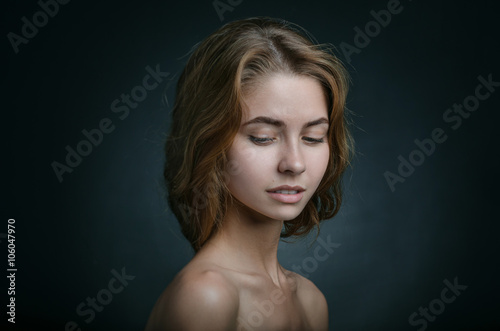 Dramatic portrait of a girl theme: portrait of a beautiful girl with flying hair in the wind against a background in studio
