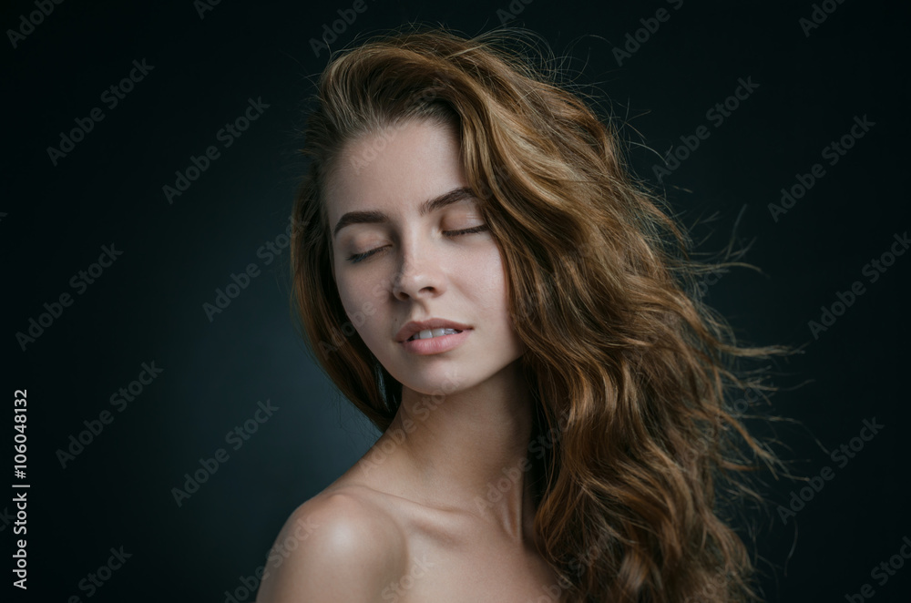 Dramatic portrait of a girl theme: portrait of a beautiful girl with flying hair in the wind against a background in studio