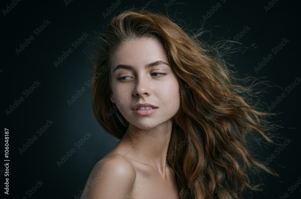 Dramatic portrait of a girl theme: portrait of a beautiful girl with flying hair in the wind against a background in studio Dramatic portrait of a girl theme: portrait of a beautiful girl with flying hair in the wind against a background in studio