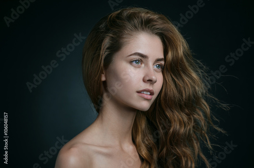 Dramatic portrait of a girl theme: portrait of a beautiful girl with flying hair in the wind against a background in studio