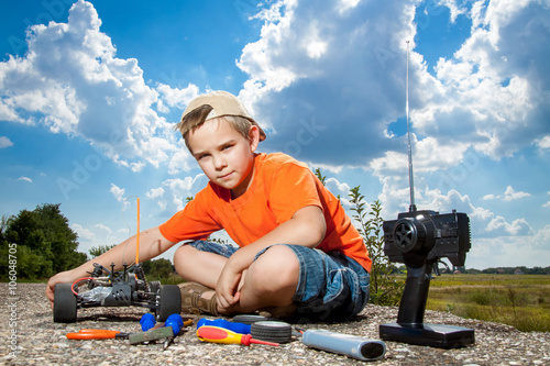 Bilde på lerret Little boy repaire the radio control car outdoor near field