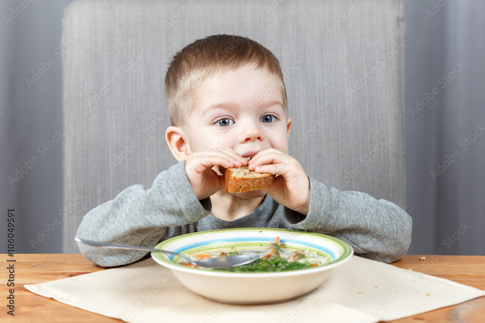 Little child bites off piece of bread at dinner Little child bites off piece of bread at dinner