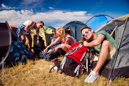 Obraz na plátně Teenagers sitting on the ground in front of tents
