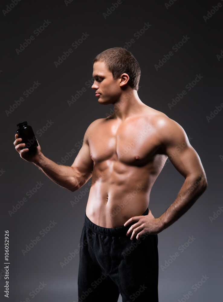 Strong, fit and sporty bodybuilder man with a bottle of sport su