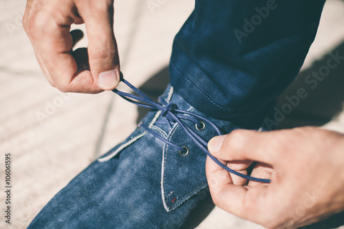 Man's hands tying shoelace of his blue shoes, Close up