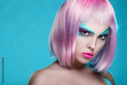 Beautiful face of puppet girl with face art in pink wig on serenity background. Ideal promotion photo