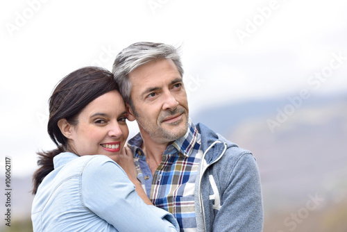 Cheerful middle-aged couple embracing outside