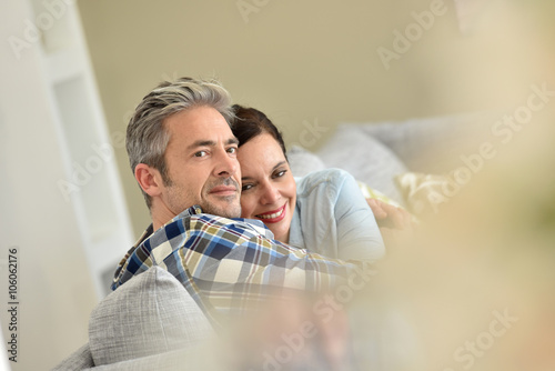 Middle-aged couple relaxing in sofa at thome photo