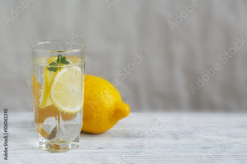 Lemonade with fresh lemon on wooden background
