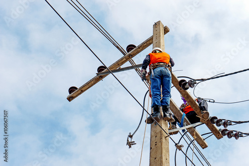 Electrician lineman repairman worker at climbing work on electric post power pole, Thai language same safty fist in English language