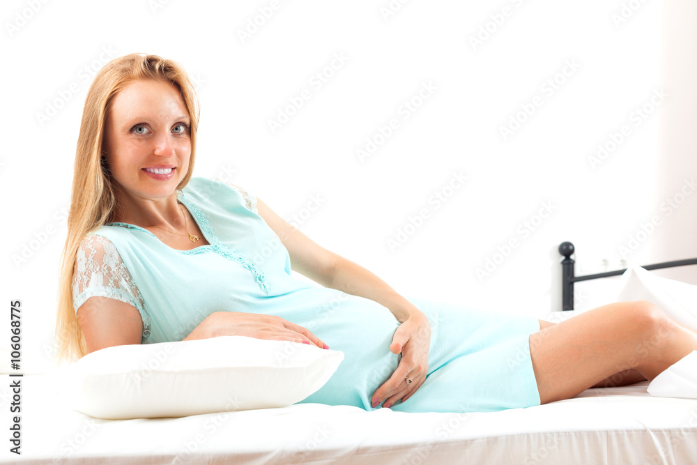 Fototapeta premium Happy pregnant woman awake on white sheet