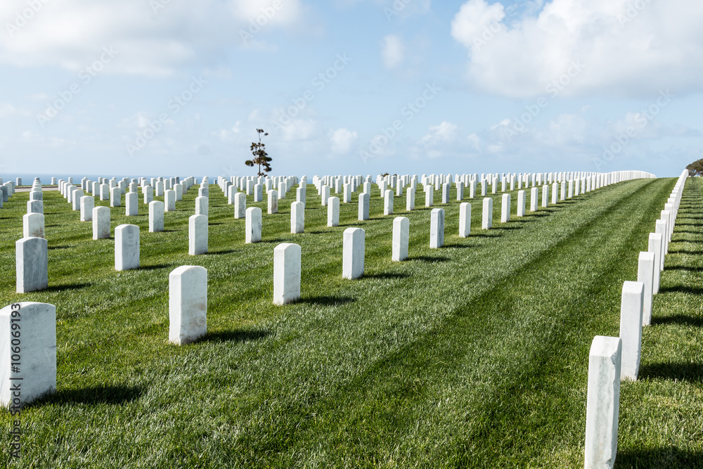 Rows of tombstones with a partly cloudy blue sky at Fort Rosecrans National Cemetery in San Diego, California. 