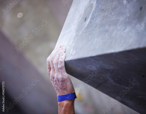 Closeup of man's hand on handhold on artificial climbing wall, hand in focus